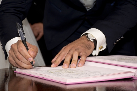 Man in suit signing his name to a book