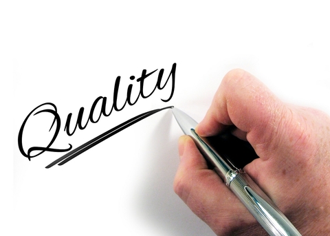 Photo of hand holding a pen writing the word quality