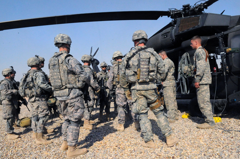Soldiers in camouflage in front of a helicopter