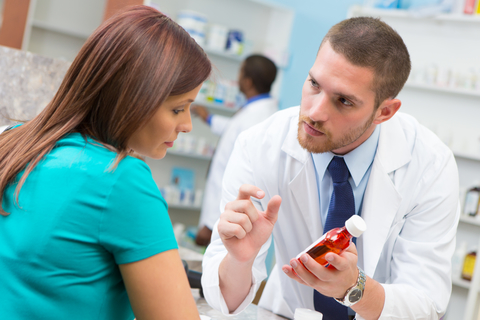 A pharmacist consulting with a patient holding medication