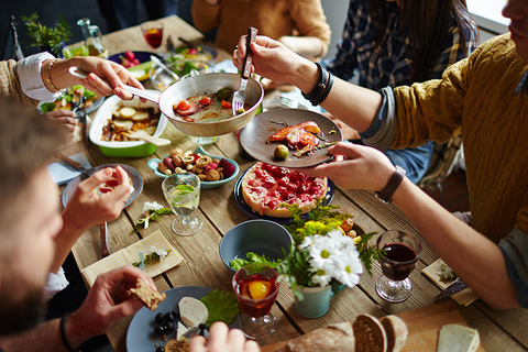 Dinner table with food - shironosov/iStock/Getty Images Plus/Getty Images Dinner table with food and people eating