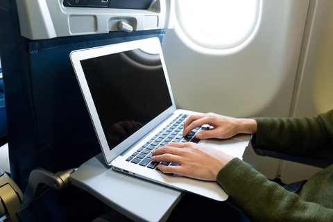 Laptop in use on plane // Photo by leungchopan/iStock/Getty Images Plus/Getty Images Laptop in use by a woman on plane