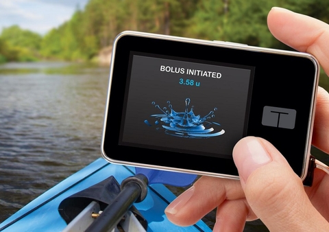 Tandem insulin pump person in kayak holding Tandem insulin pump in one hand, screen says bolus initiated