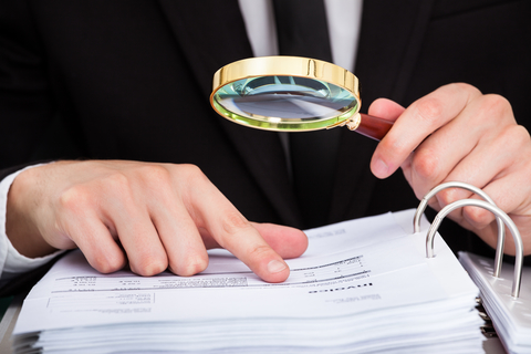 Investigator (CREDIT: Getty/AndreyPopov) Man looking at documents with magnifying glass
