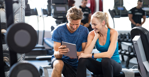 Couple in Gym Looking at a Tablet