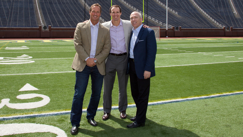 Title Boxing Club CEO John Rotche left New Orleans Saints quarterback Drew Brees center and PTMD Restaurants chairman David Barr right pose for a photo at Michigan Stadium in Ann Arbor Brees and Barr were added to the Title Boxing Club ownership group in May Photo courtesy Title Boxing Club International