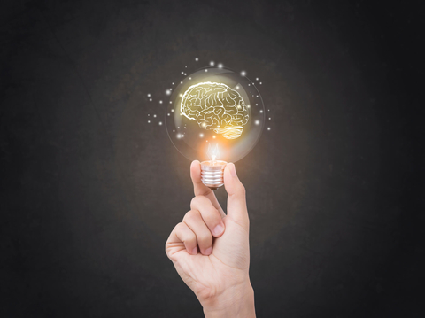 Brain inside a light bulb Hand holding a light bulb with a brain inside it
