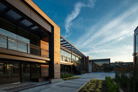 ElevateBio BaseCamp site in Waltham, MA Exterior ElevateBio BaseCamp site in Waltham, MA: A modern building of glass, wood and metal with a courtyard and blue sky in the background