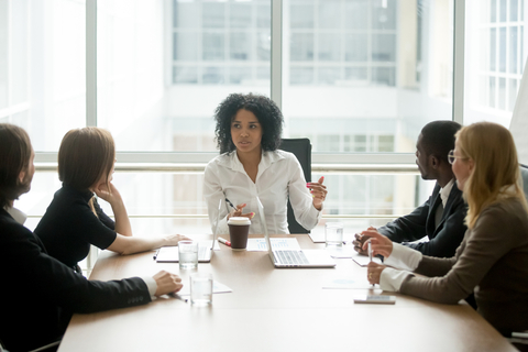 Businesswomen People around a conference table headed by a black woman