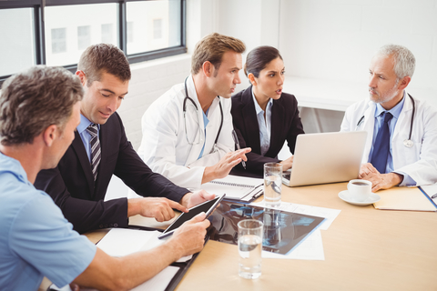 Health tech partnership Doctors and businesspeople discussing in groups with computers