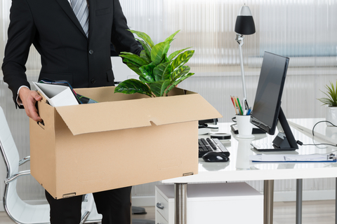 Fired executive man holding box of belongings leaving his office