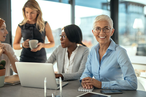 Older Worker Getty Group of female businesswomen working together on a laptop.