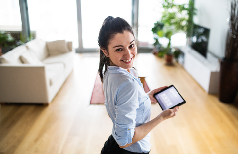 A woman holding a tablet with smart home screen at home A woman holding a tablet with smart home screen at home