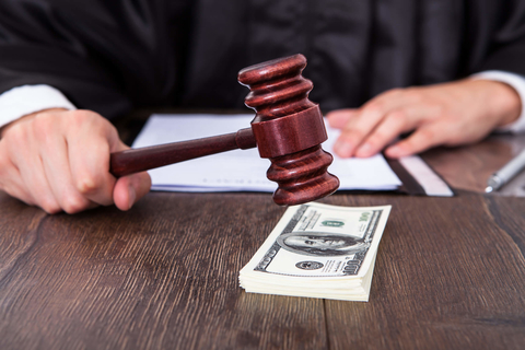 Court settlement Judge banging gavel on stack of money
