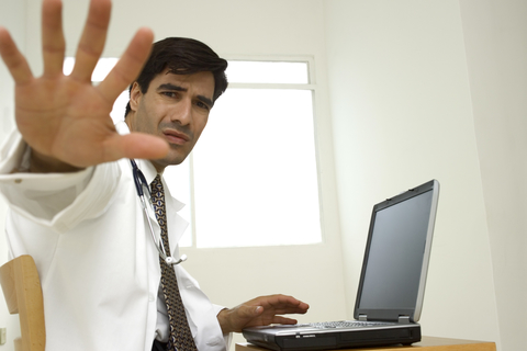 Doctor stop mad angry bully computer CREDIT: Medioimages/Photodisc A doctor at a desk holding up his hand to say stop