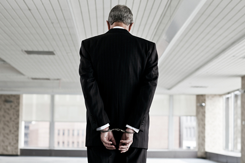 Businessman in handcuffs (Credit: Getty/Image Source) Businessman in handcuffs with his back turned