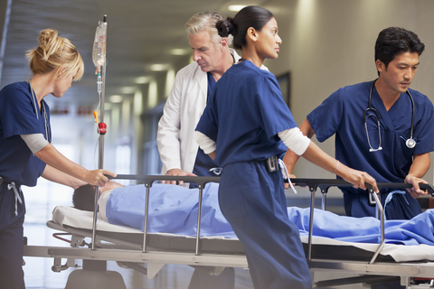 emergency doctor physician nurse patient gurney CREDIT: Getty/Sam Edwards Doctor and nurses wheeling patient in gurney through hospital corridor