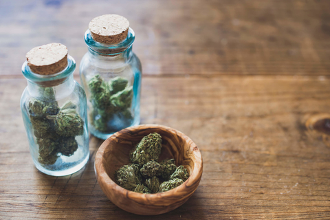 Cannabis in glass jars and wooden bowl Marijuana in glass jars and wooden bowl