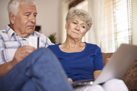 Seniors with computer Senior man and woman looking at laptop with confused expressions