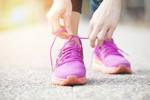 Running/walking shoes Close-up of hands tying laces on bright pink athletic shoes