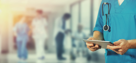 doctor with tablet photo shows torso of hospital doctor in hallway holding tablet computer