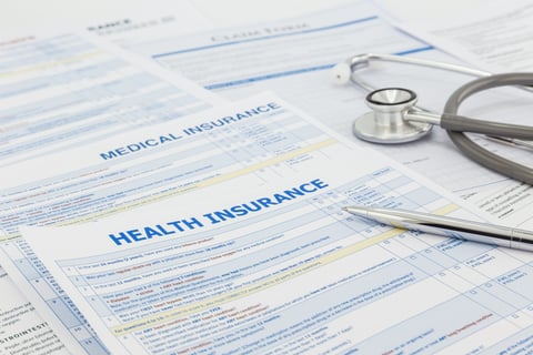 Stack of health insurance application forms with stethoscope on top
