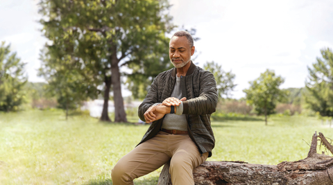 Fitbit Sense smartwatch older man places his hand over Fitbit smartwatch device to detect stress levels