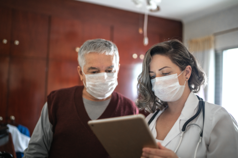 Doctor in mask Doctor in mask shows a tablet to a patient in a mask.