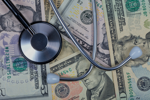 Healthcare costs Stethoscope on top of five, ten, and twenty dollar bills.