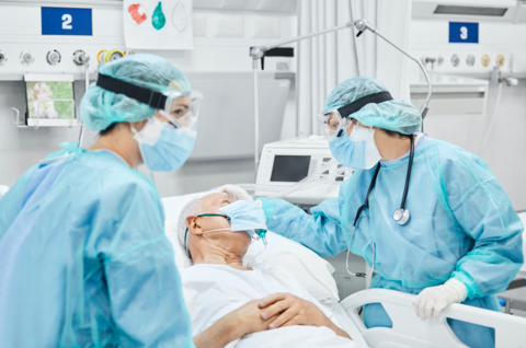 PPE Providers in PPE care for patient in hospital bed