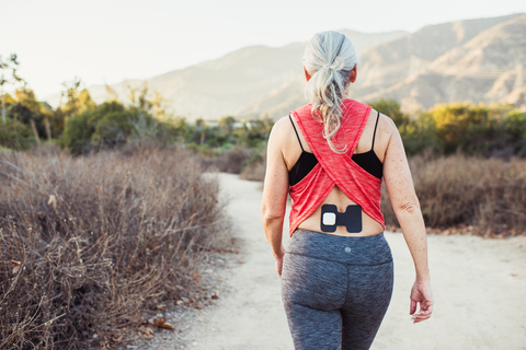 Enso noninvasive device for pain therapy An older woman outdoors hiking wears an Enso medical device on her back to alleviate pain