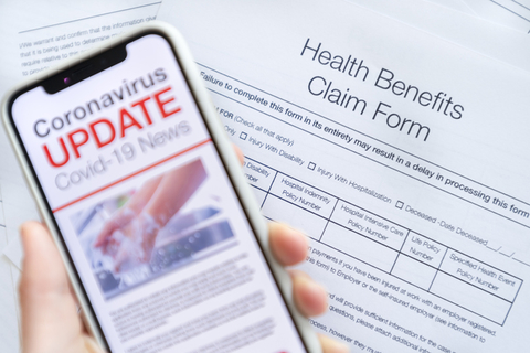 COVID-19 insurance claim A person fills out a health insurance claim while reading COVID-19 news on a phone