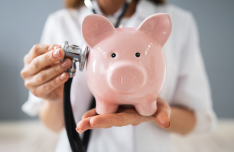 Salaries A doctor holds a stethescope to a piggy bank