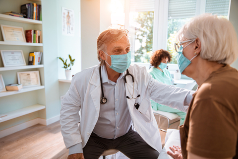 Doctor treats older woman A doctor treats an older woman while they wear facemasks