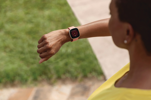 Fitbit Versa woman jogging woman checks Fitbit fitness tracker