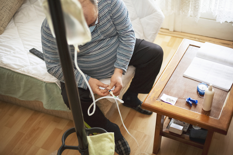 home dialysis Senior man connecting peritoneal dialysis with catheter at home