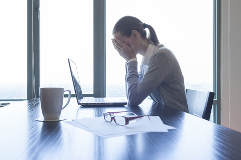 A woman at a desk feeling stress at work