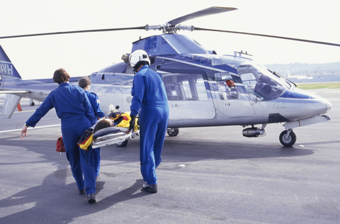 Medical helicopter Nurses and pilot carrying patient on stretcher to helicopter