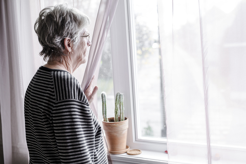 Senior loneliness An elderly woman looking out a window