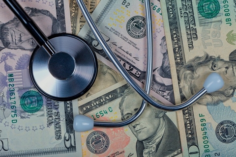 Healthcare costs Stethoscope on top of five, ten, and twenty dollar bills.