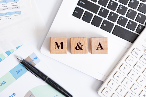 M&A concept - M&A word made with wooden blocks on laptop