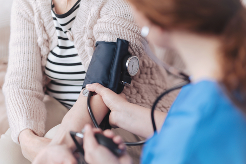 Medicare Advantage house calls nurse taking elderly patient's blood pressure