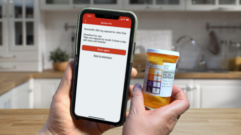 CVS Pharmacy Spoken Rx app feature hands holding a smartphone with screen shot of pharmacy app and a medication bottle