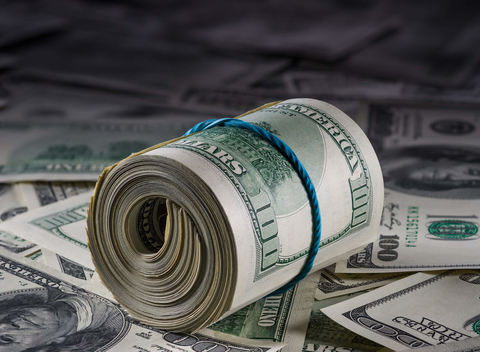 Roll of cash on pile of cash Role of hundred dollar bills on other bills