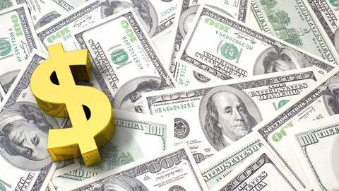 Gold dollar sign on pile of money Brass USD money sign on pile of cash