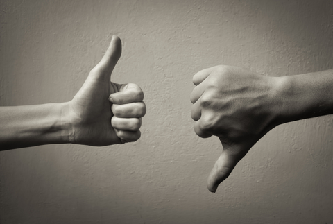 Thumbs up and thumbs down Black-and-white image of a thumbs-up hand and a thumbs-down hand in front of a blank wall.