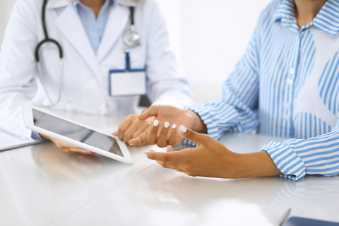 patient engagement and doctor with tablet Doctor and patient talking and discussing health treatment while sitting at the desk. Physician pointing into tablet pc.