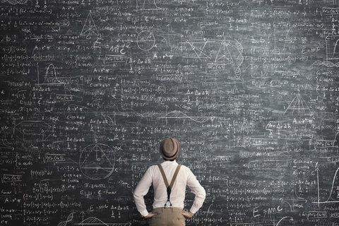Man looking up at complex math formula on chalkboard Complicated formula on chalkboard