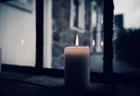 Candle in clear glass window with street in background