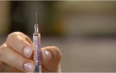 Enbrel syringe Closeup view of hand holding a prefilled syringe of Amgen drug Enbrel